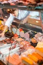 Positive male seller puts meat products on showcase