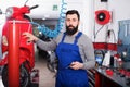 Positive male worker fixing failed motorbike Royalty Free Stock Photo