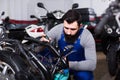 Positive male worker repairing failed scooter Royalty Free Stock Photo