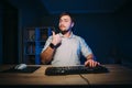 Positive man with a beard sits at night at work at home at the computer, looks at the screen, smiles and shows a thumb up. Royalty Free Stock Photo