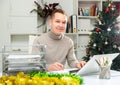 Cheerful man bookkeeper doing paperwork in Christmas decorated office