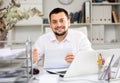 Positive man bookkeeper doing paperwork in office