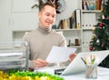 Positive man bookkeeper doing paperwork in office during Christmastime