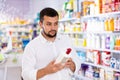 Positive man carefully studying the instructions on bottle of disinfectant