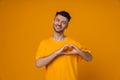 Positive man doing heart gesture and looking at camera while standing isolated Royalty Free Stock Photo