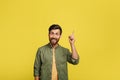 Positive man experiencing AHA moment, having creative idea or pointing finger up at copy space over yellow background