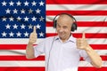 Positive man in headphones against the background of the national flag of Great Britain on delicate shiny silk with soft draperies Royalty Free Stock Photo