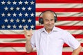 Positive man in headphones against the background of the national flag of Great Britain on delicate shiny silk with soft draperies Royalty Free Stock Photo