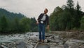 Positive man raising hands in mountain landscape. Male traveler feeling freedom Royalty Free Stock Photo