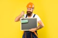 positive man renovator in helmet and work clothes hold paint roller and blackboard