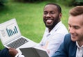 Positive man sitting on the grass with his colleague Royalty Free Stock Photo