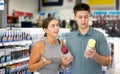 Positive man and woman choosing paint in aerosol at hardware store Royalty Free Stock Photo