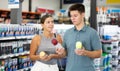 Positive man and woman choosing paint in aerosol at hardware store Royalty Free Stock Photo