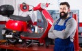 Positive man worker displaying his workplace in motorcycle workshop Royalty Free Stock Photo