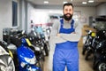 positive man worker displaying various motorcycles in workshop Royalty Free Stock Photo