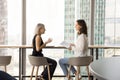 Positive mature businesswoman talking to young coworker girl Royalty Free Stock Photo