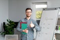 Positive mature male teacher showing thumb up standing near blackboard, recommending new online foreign languages school Royalty Free Stock Photo