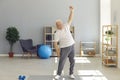 Positive mature man in home sportswear doing light exercises at home or in a rehab center.