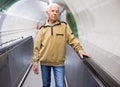 Positive mature man walking down escalator to subway station platform Royalty Free Stock Photo