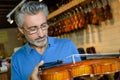 Positive middle age man purchasing traditional violins in store Royalty Free Stock Photo