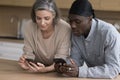 Positive middle aged multiethnic couple in love focused on smartphones Royalty Free Stock Photo