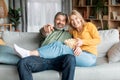 Positive middle aged spouses watching tv and eating popcorn at home Royalty Free Stock Photo