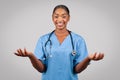 Positive millennial black doctor surgeon, nurse in blue uniform, spread hands to sides Royalty Free Stock Photo