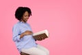 Positive millennial black pregnant lady touch belly with hand, read book, rest, enjoy motherhood Royalty Free Stock Photo