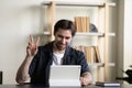 Positive millennial employee guy, tablet user waving hello at screen