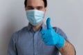 Positive millennial guy in medical face mask and latex gloves