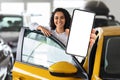 Positive middle eastern woman standing by car, showing smartphone Royalty Free Stock Photo