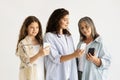 Positive millennial, old women and teen girl chatting in social networks on phones Royalty Free Stock Photo