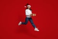 Positive Millennial Woman Wearing Santa Hat Jumping In Air With Gift Box Royalty Free Stock Photo