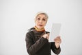 A positive modern elderly woman holds a tablet in her hands and uses it. The older generation and modern technology. Royalty Free Stock Photo