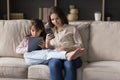 Positive mom and kid focused on gadget screens sitting close