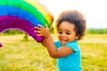 positive multicultural race little girl with afro curly hair holding rainbow balloon in summer park