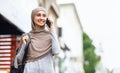 Positive muslim girl student with backpack talking on smartphone