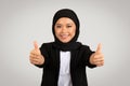 Positive Muslim woman in hijab giving two thumbs up to the camera, wearing a black blazer Royalty Free Stock Photo