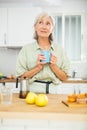 Positive old woman drinking coffee in kitchen at home Royalty Free Stock Photo
