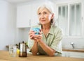 Positive old woman drinking coffee in kitchen at home Royalty Free Stock Photo