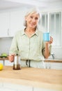 Positive old woman drinking coffee in kitchen at home Royalty Free Stock Photo