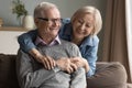 Positive older retired couple in love hugging on sofa Royalty Free Stock Photo