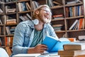 Positive overjoyed student at library burst out laughing hold book.