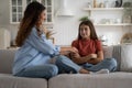 Positive parent mother cheering up sad teen girl daughter while sitting together on sofa at home Royalty Free Stock Photo