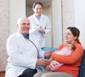 Doctors examining baby in arms of happy woman Royalty Free Stock Photo