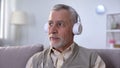 Positive pensioner in headphones listening to music, enjoying favorite radio