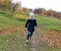 A photo of a laughing carefree little girl running on a path in an autumn park Royalty Free Stock Photo