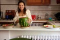 Positive pleasant housewife smiling looking at camera, slicing ripe organic juicy watermelon