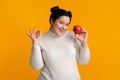 Positive Plump Girl Holding Apple In Hand And Showing Ok Gesture