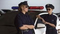 Positive police women standing near car, talking and smiling, break from work